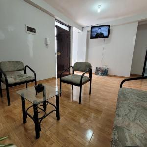 a living room with two chairs and a table and a tv at Apartamento viaje de estudio in Huancayo