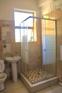 a bathroom with a shower with a toilet and a sink at Grandborough in Durban