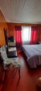1 dormitorio con cama, silla y cortinas rojas en ALOJAMIENTO LAS LILAS en Cartagena