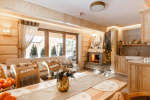 a kitchen and living room with a table and a fireplace at Brzozowa Osada - Premium Chalets Zakopane in Zakopane