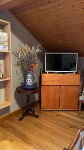 - une télévision au-dessus d'un meuble en bois avec une table dans l'établissement Chambre dans Maison Campagnarde, à Présilly