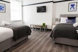 a bedroom with two beds and a table and a television at Bootle, Liverpool Modern 1Bed Ft in Liverpool