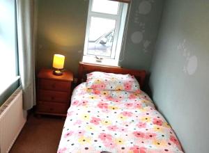 a small bedroom with a bed with a window at Bwthyn Bach (Tiny Cottage) in Wrexham