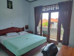 a bedroom with a bed and a large window at Celagi Inn in Padangbai