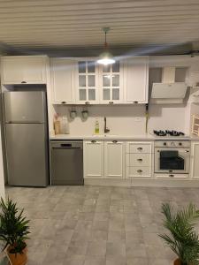 a kitchen with white cabinets and a stainless steel refrigerator at HOUSE KA TEKKE ROOM in Canakkale