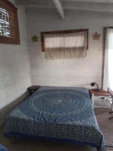 ein Schlafzimmer mit einem Bett mit einer blauen Decke darauf in der Unterkunft El Descanso in Neptunia
