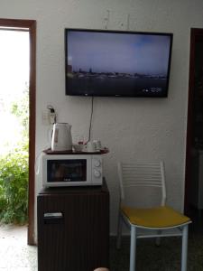 a tv on a wall with a microwave and a chair at Suíte in Punta del Este