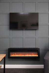 a fireplace with a television on a wall at The Blue House by Luke Stays in Bearpark