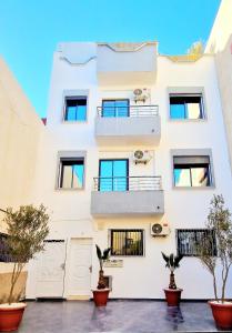 un bâtiment blanc avec des plantes devant lui dans l'établissement Beach Appartment close to Marina 105 sqm, à Agadir