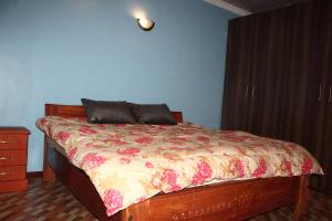a bedroom with a bed with a floral bedspread at Ms Safari in Thika