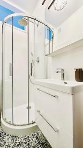 baño blanco con ducha y lavamanos en Baja Apartment Warsaw, en Varsovia