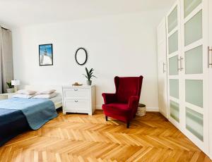1 dormitorio con 1 cama y 1 silla roja en Baja Apartment Warsaw en Varsovia