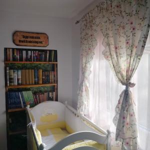 1 dormitorio con cuna y ventana con cortinas en Vujanac vikend kuća en Raška