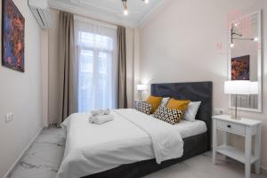 a white bedroom with a large bed and a window at Ω Omega, Nilie Hospitality MGMT in Thessaloniki
