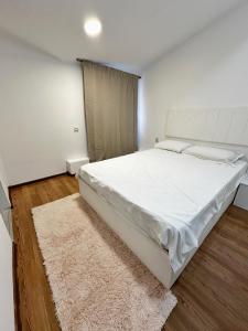 a bedroom with a large white bed and a rug at Stone Residence in Braşov