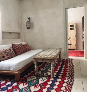 a room with a bed and a bench on a rug at Apartamentos Caravane in Tarifa