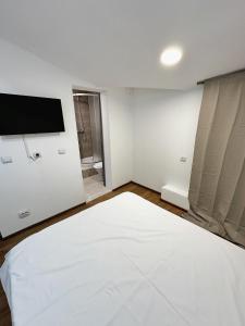 a white room with a bed and a flat screen tv at Stone Residence in Braşov