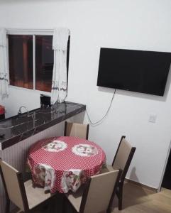 a dining room with a table and chairs and a television at Chalé Ilhabela in Ilhabela