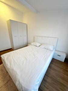 a bedroom with a large bed with white sheets at Stone Residence in Braşov