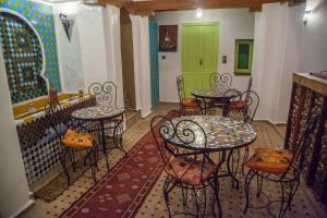 a room with tables and chairs and a green door at Riad Merzouga in Fez