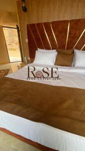a bed with a wooden headboard with the word rojas on it at Wadi Rum Rose camp in Wadi Rum