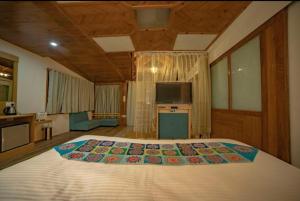een slaapkamer met een groot bed en een televisie bij Aman The Lake Side Hotel in Nainital