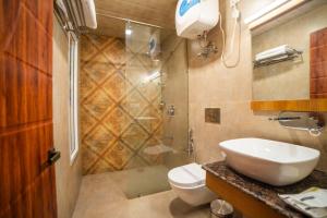 a bathroom with a shower and a toilet and a sink at Aman The Lake Side Hotel in Nainital