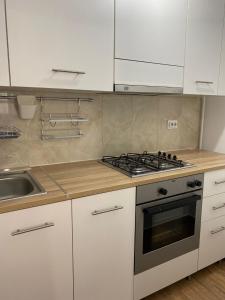 a kitchen with white cabinets and a stove and a sink at Orizont-Livezeni in Livezeni