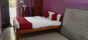 uma cama com almofadas vermelhas e brancas num quarto em Sri Sekars Rooms em Villianur
