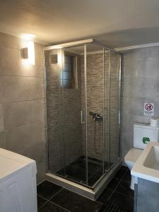La salle de bains est pourvue d'une douche avec une porte en verre. dans l'établissement Serene Apartment with Breathtaking Sea View, à Thessalonique