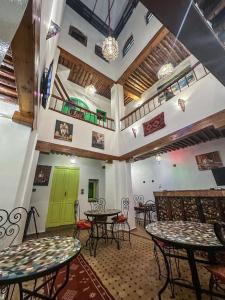 uma sala com mesas e cadeiras e uma porta verde em Riad Merzouga em Fez