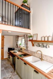 a kitchen with a sink and a staircase at Woodman's Cottage in Temple Ewell