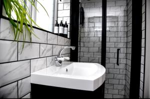 lavabo blanco en un baño blanco y negro en Woodman's Cottage en Temple Ewell