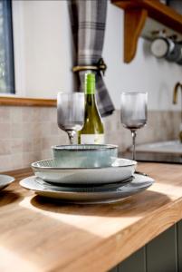 Woodman's Cottage في Temple Ewell: طاولة مع الأطباق وكؤوس النبيذ على منضدة