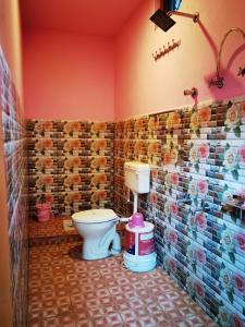 a bathroom with a toilet and flowers on the wall at Holiday Home Chopta Tungnath in Ukhimath