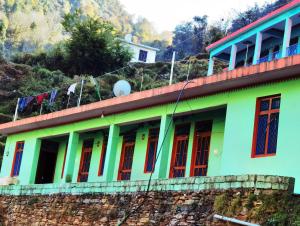 a green building with red doors on a hill at Holiday Home Chopta Tungnath in Ukhimath