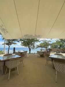 un patio vacío con mesas y sillas y el océano en The Beach Suite at The Mactan Newtown, en Lapu Lapu City