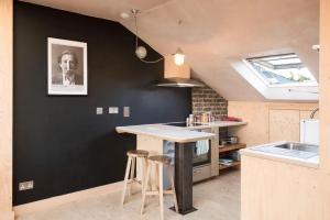 une cuisine avec des murs noirs, une table et des tabourets dans l'établissement Stunning studio loft in Brixton, London, à Londres