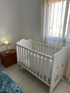 a white crib in a bedroom with a window at Málaga Capital - Zona Oeste: Parking-Wifi-Piscina in Málaga