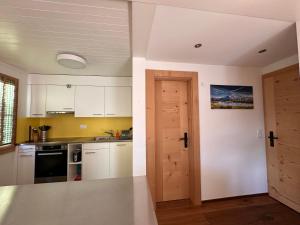 a kitchen with white cabinets and an open door at Chalet Solaria 2 bedrooms with mountain and garden view in Zweisimmen