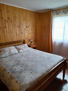 a bedroom with a bed with a wooden wall at Cabañas encanto de Chovellen in Pelluhue