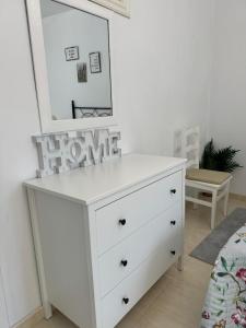 - une commode blanche avec un miroir au-dessus dans l'établissement Apartamento O Vento, à O Grove