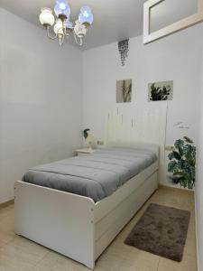 - une chambre blanche avec un lit blanc et un lustre dans l'établissement Apartamento O Vento, à O Grove