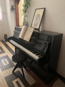 a black piano with a chair and a picture at Au coeur de Tana, vue sur le Palais de la Reine, en securité in Antananarivo