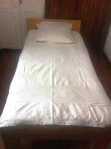 1 cama no hecha con sábanas y almohadas blancas en Au coeur de Tana, vue sur le Palais de la Reine, en securité, en Antananarivo