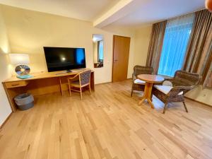 Cette chambre d'hôtel dispose d'un bureau avec une télévision et des chaises. dans l'établissement Hotel Restaurant Steinkrug, à Wennigsen