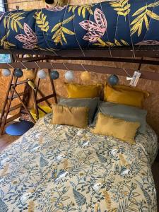 a bed with yellow pillows on top of it at La Maison Cahour in Redon