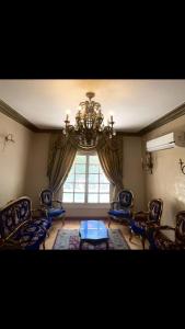 a living room with blue chairs and a chandelier at Sheikh zayed Tata in Sheikh Zayed