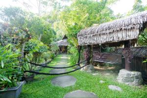 une maison avec un toit de chaume et un chemin dans l'établissement Green Travelodge Bukit Lawang, à Bukit Lawang