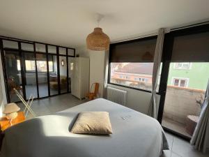 a bedroom with a bed and a large window at L’appartement du bonheur in Issoire